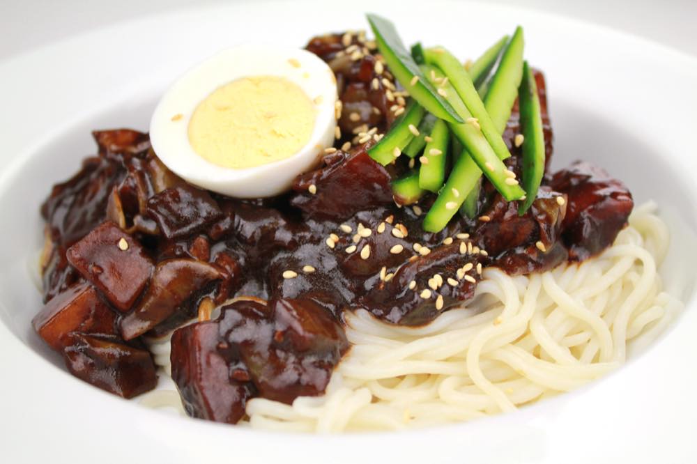 A bowl of jjajangmyeon topped with a fried egg, similar in style to Sinseung Banjeom's signature uni jjajang