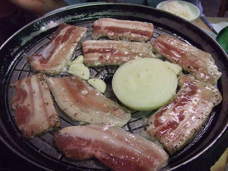 Korean samgyeopsal pork belly grilling on a tabletop grill, the dish Chupungryeong Kal Samgyeopsal in Apgujeong is known for