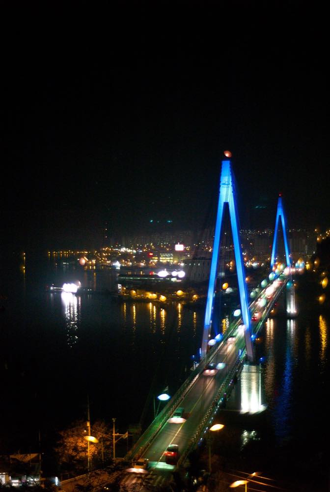 Orange tented food stalls at Nangman Pocha Street in Yeosu, South Korea, lit up at night along the harbor