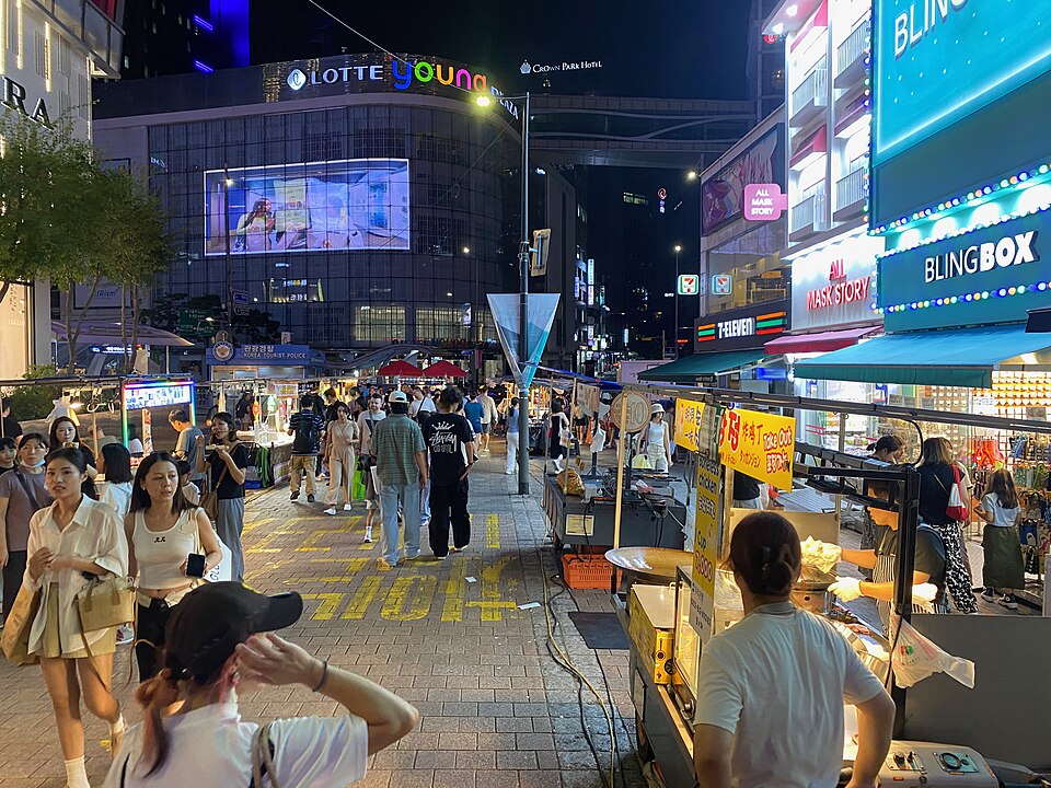 Evening crowd walking past street food carts in Myeongdong, Seoul