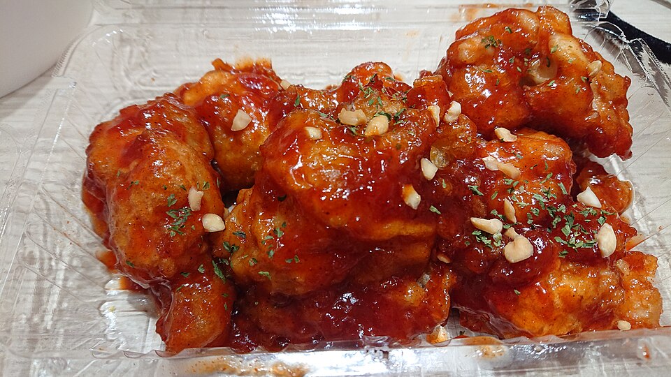 Takeaway box of sweet and spicy glazed fried chicken, a popular Korean street snack