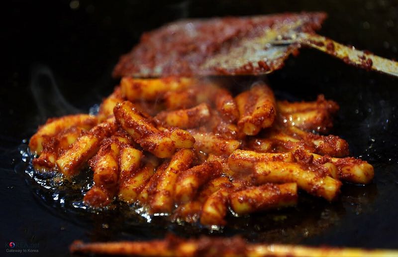 Oil-fried gireum tteokbokki rice cakes cooking on a griddle at Tongin Market in Seoul